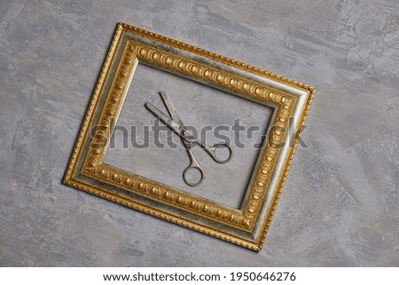Old scissors in a bronze frame and a gray background. 