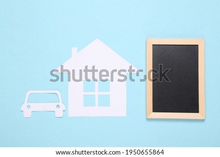 Paper-cut house and car, chalk board on a blue background. Property. Copy space