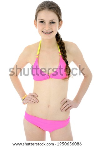 Beautiful teenage girl wearing a pink bikini in studio isolated on white