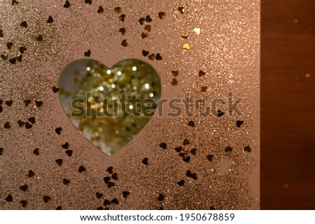 The composition features a heart on a background with glitter, filings of golden flashes of light. In natural style in colors of white, gold, silver, pink.