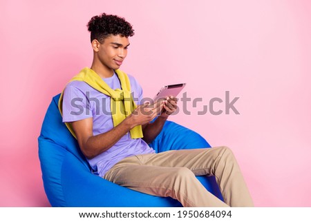 Profile side photo of young african man sit beans chair browse tablet isolated over pink color background