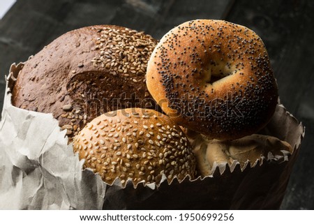Various types of characteristic and typical bread inside a paper bag, isolated on a wooden table
