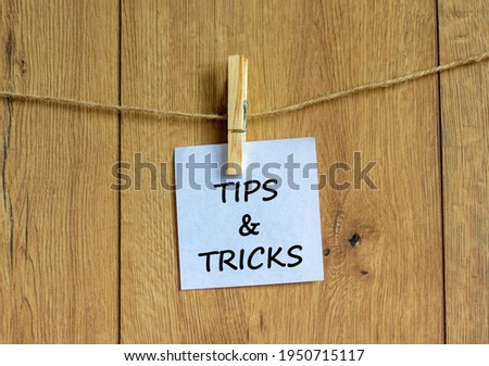 Tips and tricks symbol. White paper on wooden clothespin. Words 'Tips and tricks'. Beautiful wooden background. Business and tips and tricks concept, copy space.
