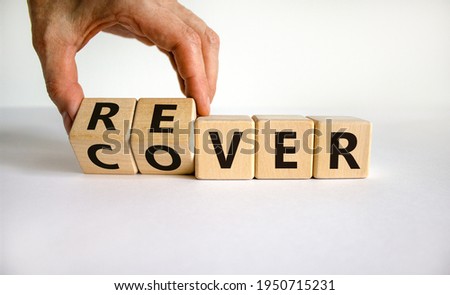 Recover symbol. Concept word 'recover' on wooden cubes on a beautiful white table. Businessman hand. White background. Business and recover concept. Copy space.