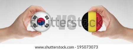 Man's hands holding styrofoam balls with Korean and Belgian flag against the white background.