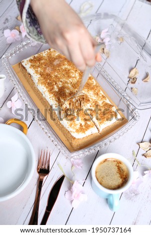 Hazelnut milk cake with hazelnut and sauce on the top an cup of coffee on white wood background 