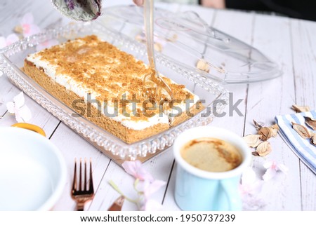 Hazelnut milk cake with hazelnut and sauce on the top an cup of coffee on white wood background 