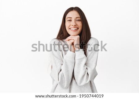 Romantic and cute girl looking with admiration and sympathy, admire something, watching beautiful lovely scene, resting head on hands and smiling, standing over white background