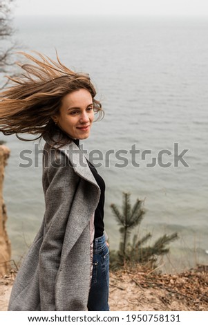 beautiful girl dressed in a gray coat on the background of the Baltic Sea