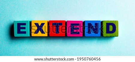 The word EXTEND is written on multicolored bright wooden cubes on a light blue background