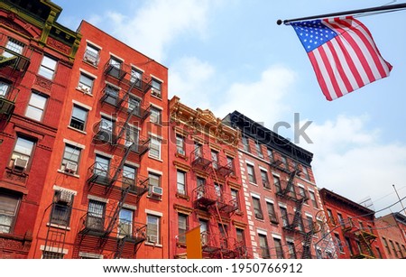Old brick buildings with fire escapes and American Flag, New York City, USA.
