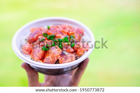 Spicy fish Ahi poke bowl on natural green background.  Royalty-Free Stock Photo #1950773872