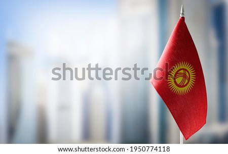 A small flag of Kirghizia on the background of a blurred background