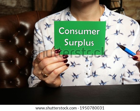 Young Woman holding a blank card in hands. Conceptual photo about Consumer Surplus with written text.
