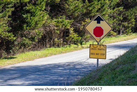 Beat up traffic sign on a creepy old road with fence and overgrown trees. Concept of danger ahead.
