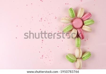 Fresh colorful macaroons on a light table with crumbs, top view, place for text. Modern bakery concept, business card for advertising or invitation. Delicious traditional breakfast, selective focus