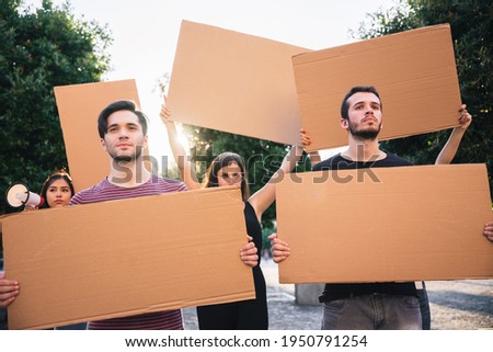Group of protesters during a concept procession with empty signs to be filled with personal graphics - Millennials in a public demonstration in the city at sunset - Copy space