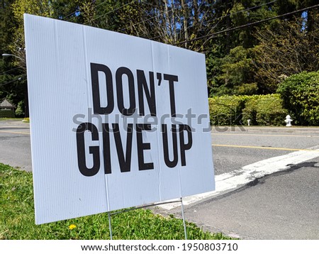 Angled view of a Don't Give Up motivational sign in a yard during the COVID-19 pandemic