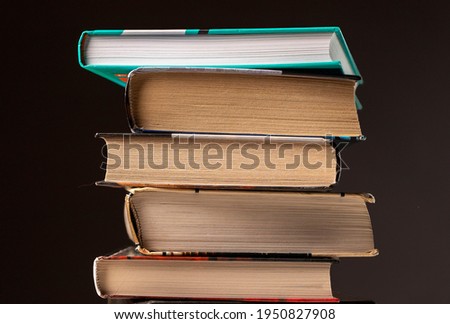 Pile or stack of books, literature, textbooks on dark background.