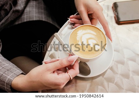 Girl in a cafe holding a cup of coffee with milk. High quality photo