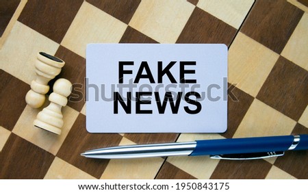 Business card with text Fake News on a chess board with pen and eyeglasses. Concept photo