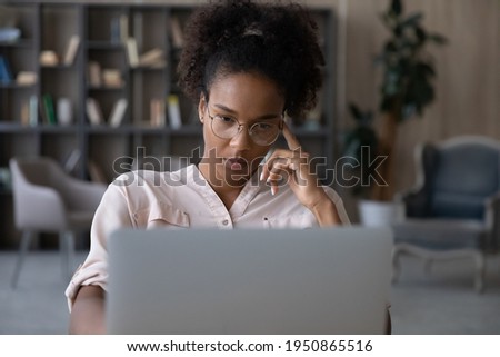 Pensive young biracial woman in glasses look at laptop screen work online think of problem solution. Thoughtful millennial African American female unmotivated to do computer job. Laziness concept. Royalty-Free Stock Photo #1950865516