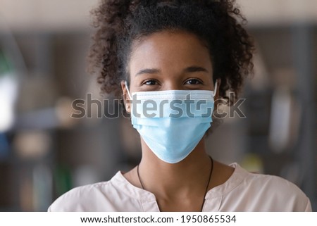 Close up portrait of smiling African American woman in facemask protect from coronavirus. Headshot of happy biracial female in facial mask against corona virus. Covid-19, healthcare concept. Royalty-Free Stock Photo #1950865534