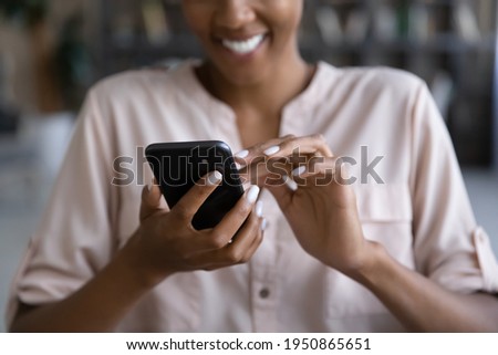 Crop close up of smiling biracial woman hold use modern cellphone text message online on gadget. Happy African American female browse internet or have webcam video talk on smartphone device. Royalty-Free Stock Photo #1950865651