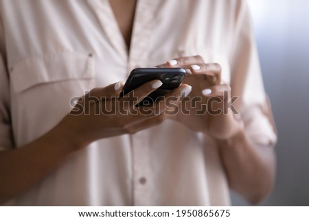 Crop close up of African American woman hold use modern smartphone gadget browse wireless internet on device. Biracial female text message on cellphone. Technology, communication concept. Royalty-Free Stock Photo #1950865675