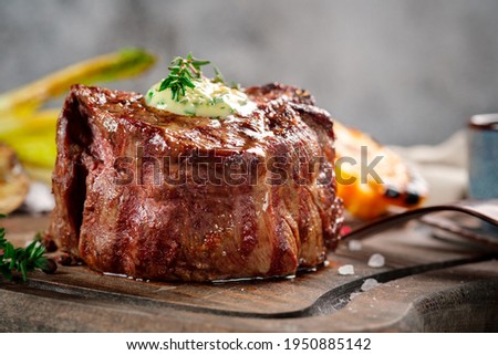 Large grilled Filet Mignon steak with butter and thyme served on a wooden board. Roast meat dish, close up Royalty-Free Stock Photo #1950885142