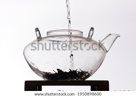 Silhouette of water pouring in clear glass teapot on white background