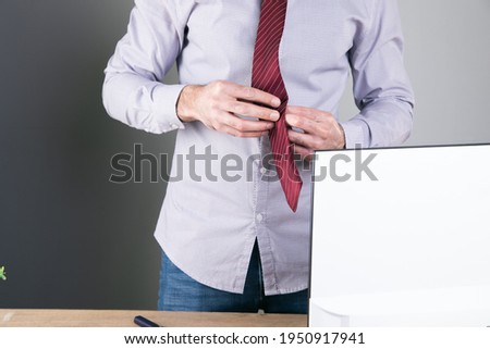 man straightens his tie on a gray background .