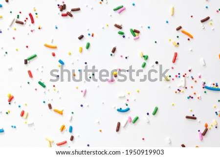 Colorful edible sugar sprinkles background - seamless pattern on white background. Spoons whith colorful sprinkles.
