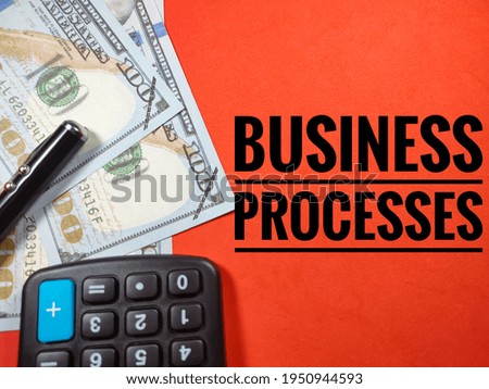 Business concept.Text BUSINESS PROCESSES with pen,banknote and calculator on red background.