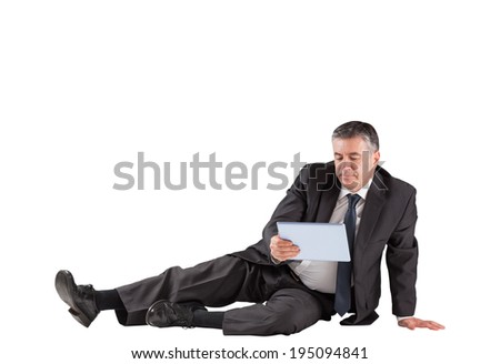 Concentrating businessman lying on floor using tablet on white background