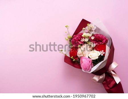 A bouquet of flowers placed on a pink background. Viewed from directly above.