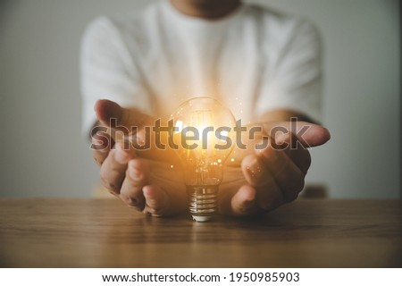 Hand holding light bulb on wood table. Concept of inspiration creative idea thinking and future technology innovation Royalty-Free Stock Photo #1950985903