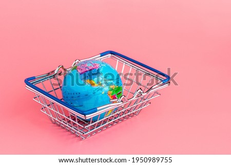 Small globe in a Shopping cart on a pink background. USA, Mexico and South America are pictured. Online shopping