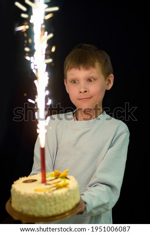 Portrait of an 8-10-year-old boy on his birthday with a birthday cake and a candle, selective focus