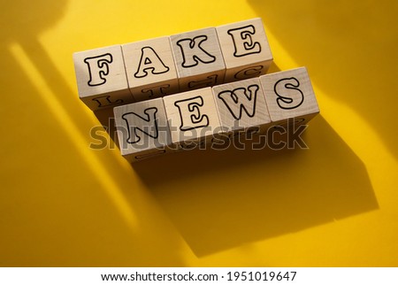 On a yellow background with shadows on the cubes, the inscription is fake news.