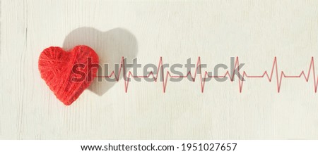 Red heart made of wool threads on a light wooden background with cardiogram. High quality banner