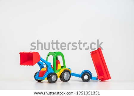 Children's toy plastic car isolated on white background. Multi-colored excavator with a trailer.