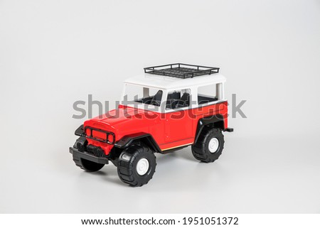 Children's toy plastic car isolated on white background. Red and white SUV.