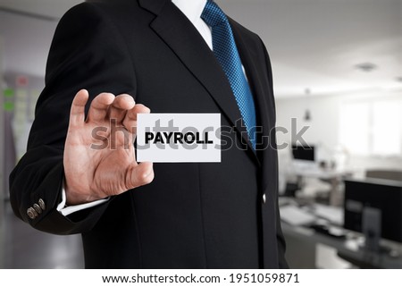 Businessman shows a business card with the word payroll. Business finance concept.

