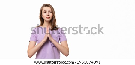 Attractive girl with folded hands asking help or forgiveness, praying with hope, isolated on white background. True human reactions, emotions and feelings