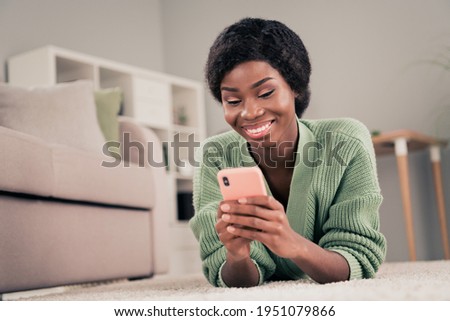 Low angle view photo of young cheerful black woman happy positive smile read post chat type sms smartphone home