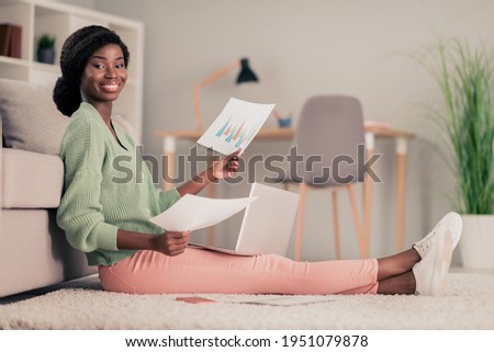 Full length body size photo girl preparing for exams smiling sitting on floor keeping papers studying in college