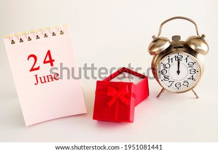 calendar date on light background with red gift box with ring and alarm clock with copy space. June 24 is the twenty-fourth  day of the month.