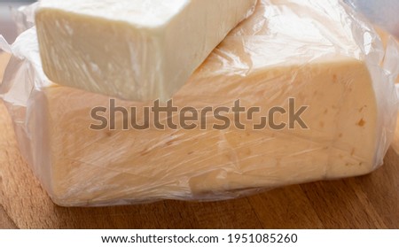 farm, dairy products, a piece of butter and cheese, wrapped in plastic wrap, lie on a wooden board, on a light background. Food, Vegan Oil, Healthy Eating, Daily Diet, Dairy Benefits