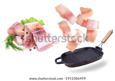 A steak of flying fish falls into the pan. The effect of flying motion in the cooking process.Isolated objects on a white background. Flying food.